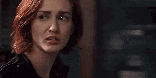 a close up of a woman 's face with red hair and a black jacket .