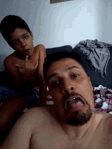 a shirtless man is making a funny face while a boy looks on