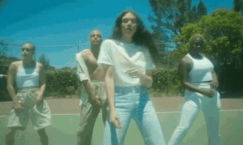 a group of people are dancing on a tennis court including a woman in a white shirt