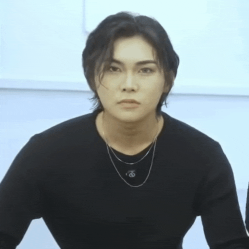 a young man wearing a black sweater and a necklace with the letter o on it