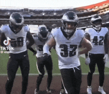 a group of football players are dancing on the field and one of them has the number 32 on his jersey