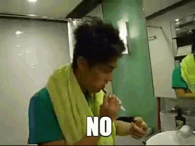 a man with a yellow towel around his neck is smoking a cigarette in a bathroom and says no .