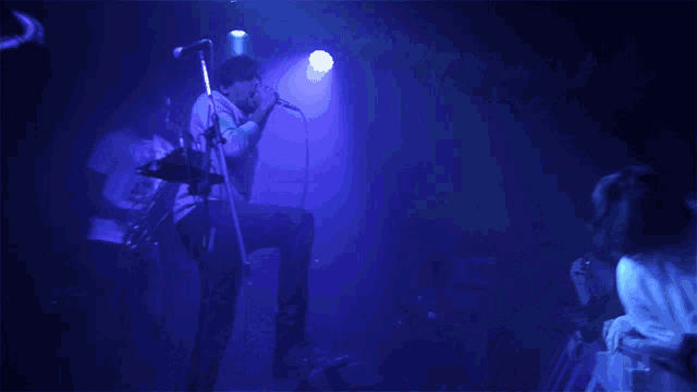 a man singing into a microphone in front of a crowd of people