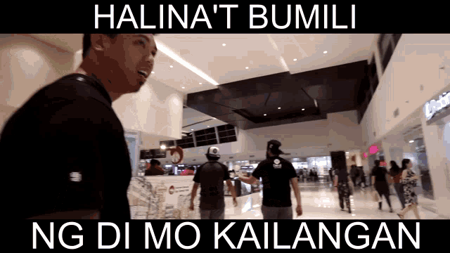 a man in a black shirt stands in front of a sign that says halina 't bumili ng di mo kailangan