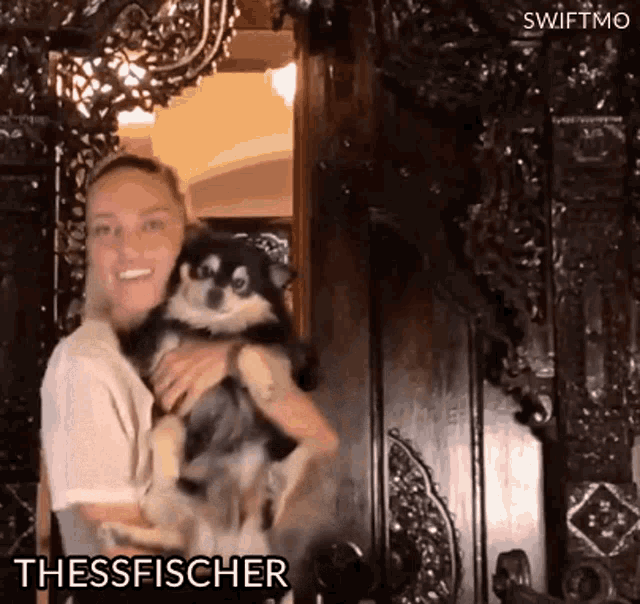 a woman is holding a small dog in her arms and the dog is named thessfischer