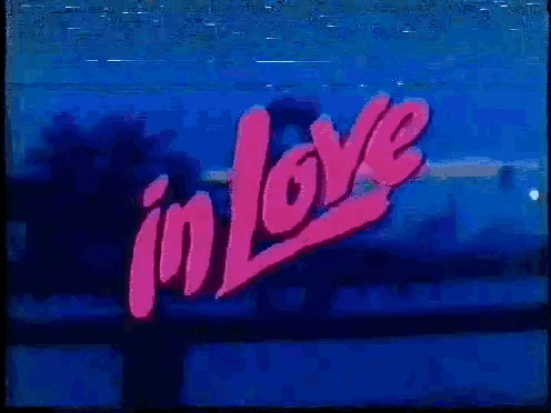 a neon sign that says `` in love '' is lit up in pink and red .