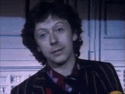 a man with curly hair is wearing a striped jacket and tie