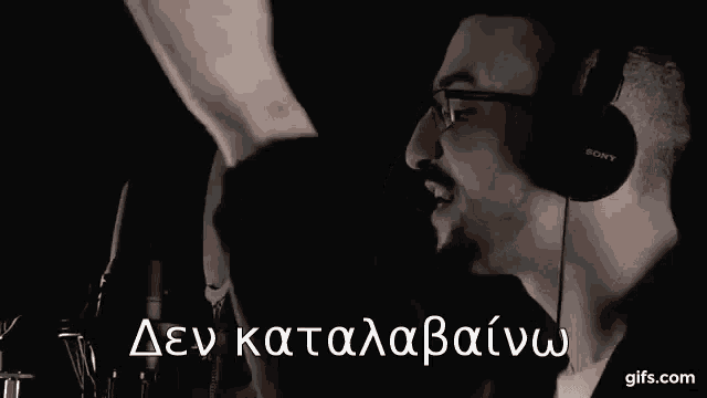 a man wearing headphones and glasses is singing into a microphone in a dark room .