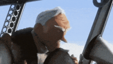 a man with gray hair and a beard is sitting in a cockpit of an airplane