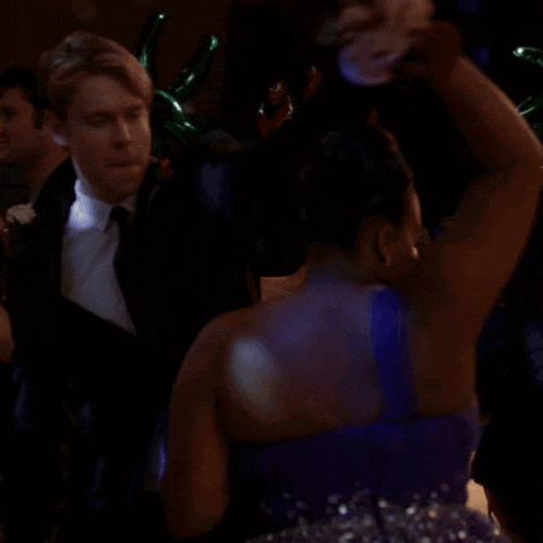 a woman in a blue dress is dancing with a man in a tuxedo