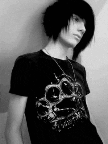 a young boy with long black hair is wearing a black t-shirt with a skull on it and a necklace .