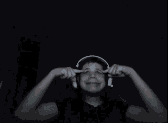 a person wearing headphones covering their ears in the dark