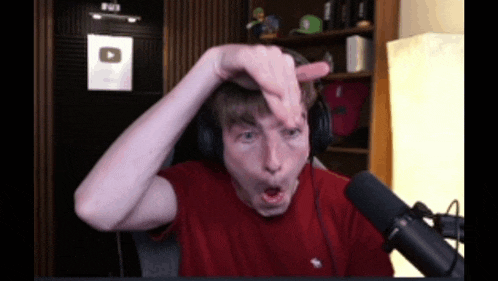 a man wearing headphones and a red shirt is making a face in front of a microphone