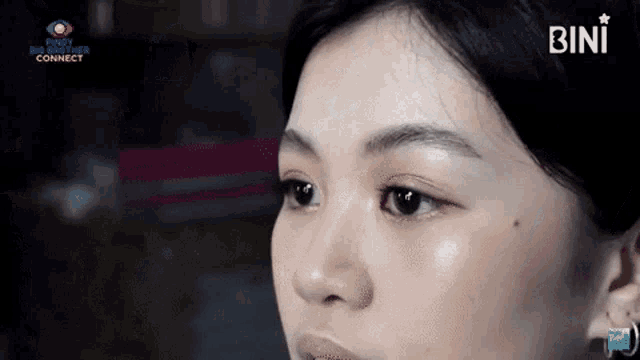 a close up of a woman 's face with the word bini on the bottom