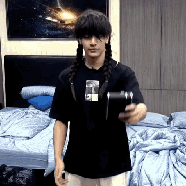 a man wearing a braided wig and a black t-shirt with the letter r on it