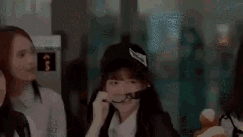 a group of girls are sitting at a table eating ice cream . one of the girls is wearing a hat .