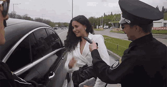 a woman is talking to a police officer in front of a gas station that says " byommin "