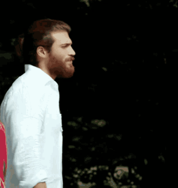 a man with a beard wearing a white shirt stands next to a woman in a red dress