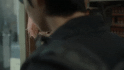 a young man with pink hair is looking at himself in a mirror
