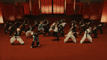 a man in a leather jacket is standing in front of a group of people dancing in a room .