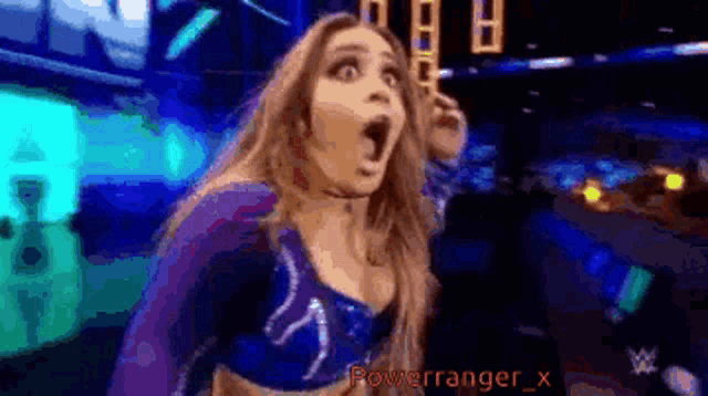 a woman with a surprised look on her face is standing in a dark room with her mouth open .