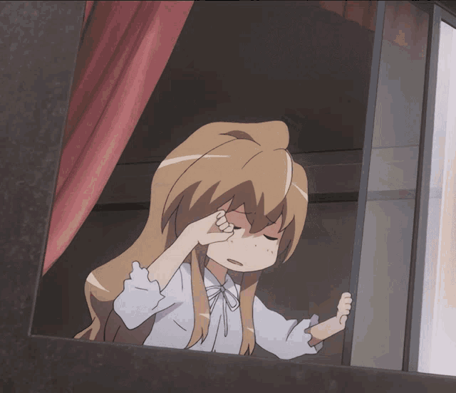a girl is looking out of a window and covering her face with her hand