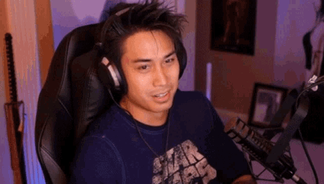 a man wearing headphones is sitting in a chair in front of a microphone in a room .