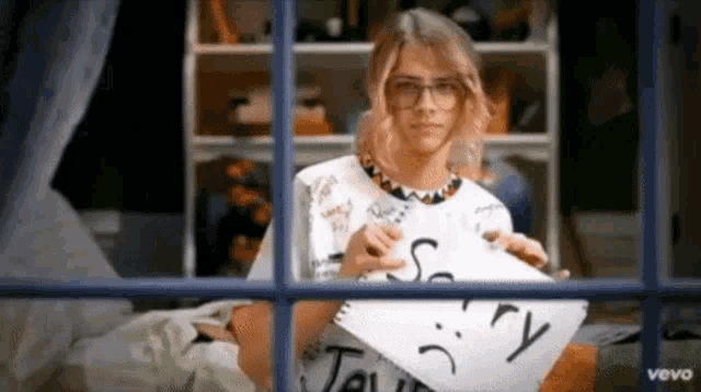 a girl is holding a piece of paper that says " sorry "