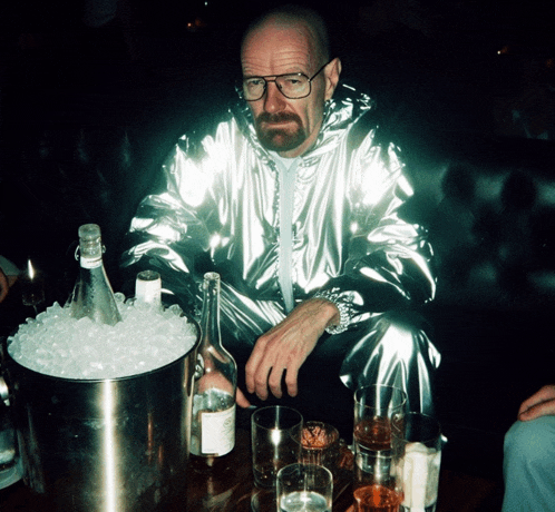 a man in a silver suit sits at a table with a bucket of ice