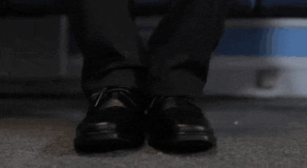 a man in a suit and black shoes is sitting on a chair .
