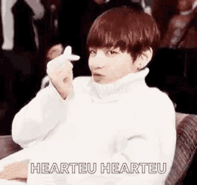 a young man is making a heart sign with his hand .