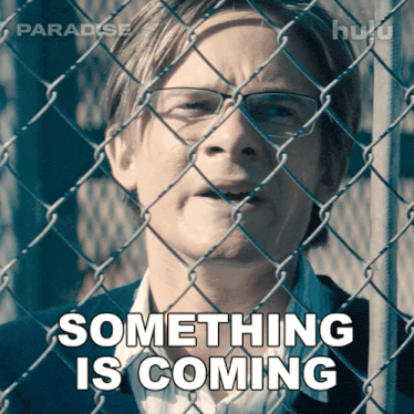 a man behind a chain link fence with something is coming