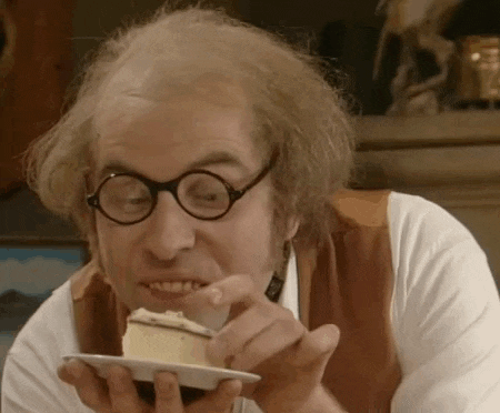 a bald man wearing glasses is eating a piece of cake .