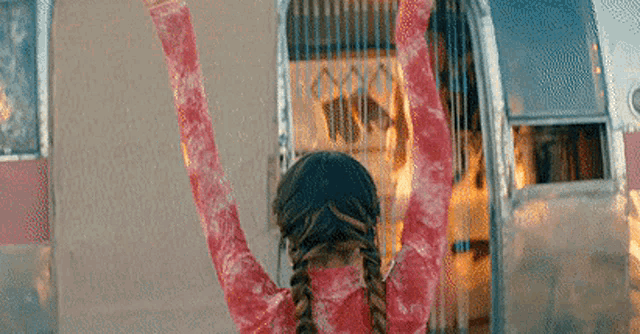 a woman in a red shirt and goggles is standing in front of a trailer with her arms in the air .