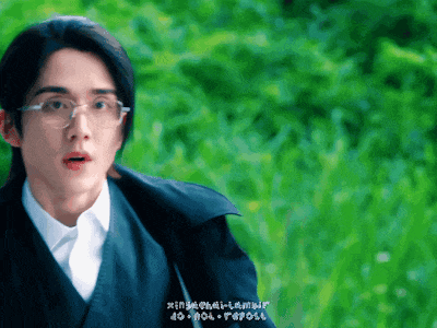 a man wearing glasses and a black jacket stands in front of a green background