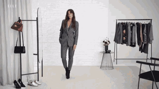 a woman in a suit is standing in front of a mirror with the word elle on the bottom right
