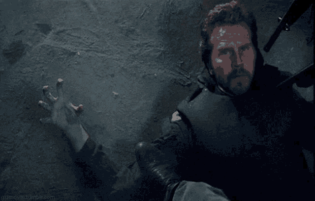 a man with a beard is laying on the ground with his arm extended