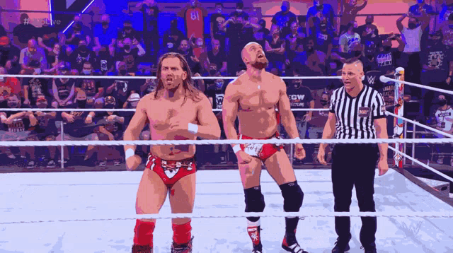 two wrestlers are standing in a ring with a referee and a crowd watching