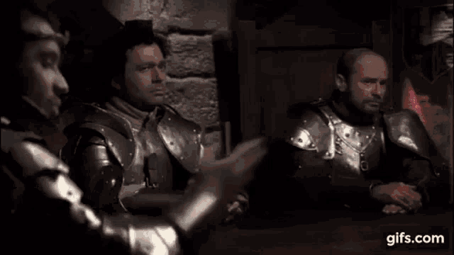 a man in armor is sitting at a table with another man .