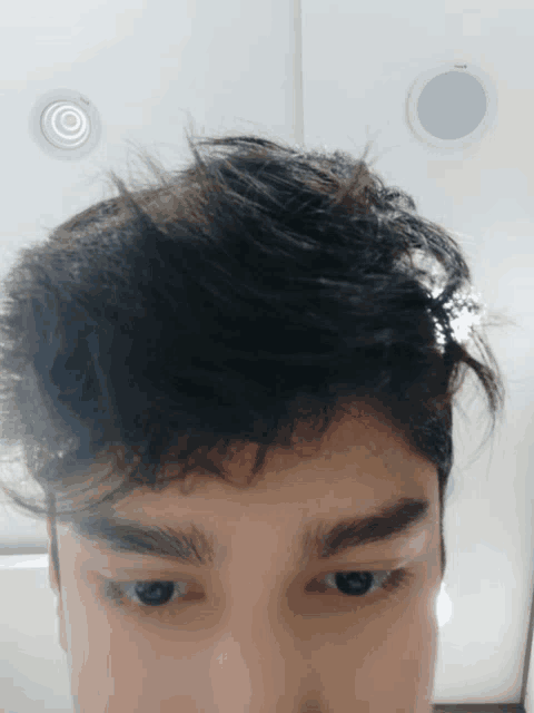 a close up of a young man 's face with a white ceiling in the background