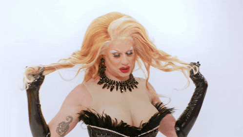 a drag queen with blonde hair and a tattoo on her arm