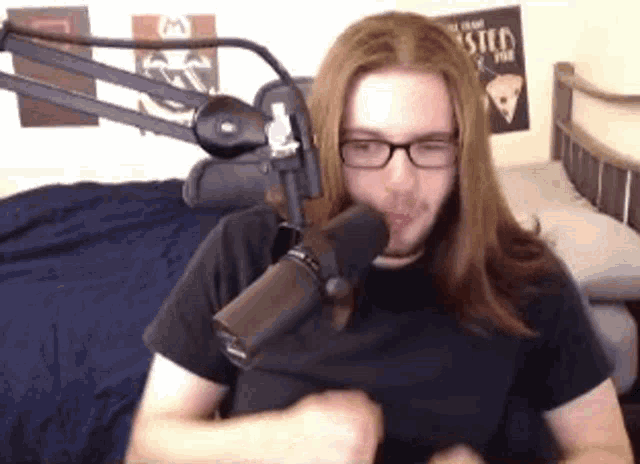 a man with long hair is sitting in front of a microphone .