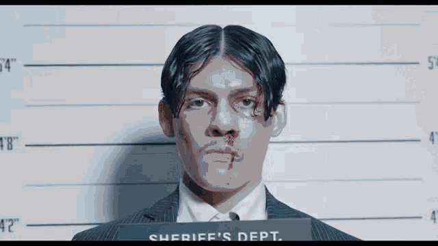 a man in a suit and tie is standing in front of a sheriff 's department photo .