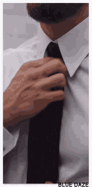 a man in a white shirt is adjusting his tie