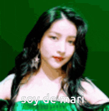 a woman in a green dress is standing in front of a green background with the words soy de mari written on it .