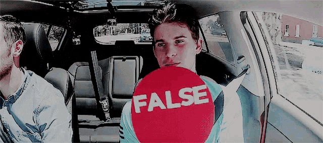 a man in a car holds a false sign in his hand