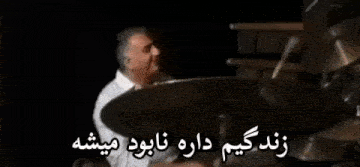 a man is playing drums in a dark room with a foreign language .