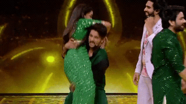 a man is carrying a woman in his arms on a stage while other people watch .