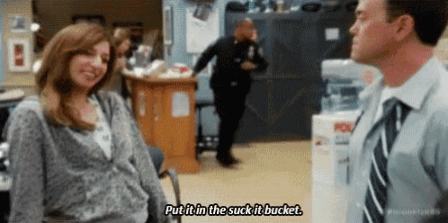 a man and a woman are talking to each other in an office while a police officer runs in the background .