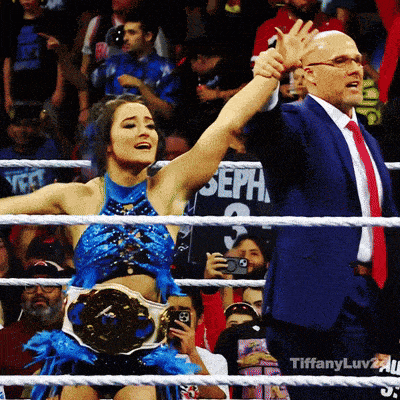 a man in a suit and tie stands next to a woman in a blue dress with her arm in the air